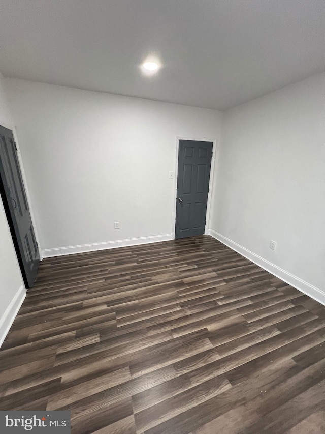 unfurnished room with dark wood-type flooring