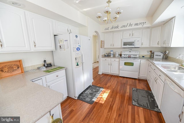 kitchen featuring white appliances, dark wood-type flooring, sink, a notable chandelier, and white cabinets