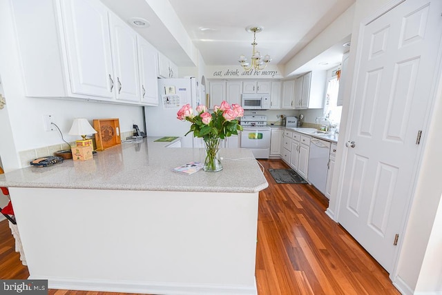 kitchen with pendant lighting, white appliances, kitchen peninsula, and white cabinets