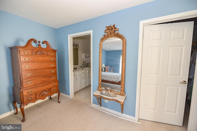 bedroom featuring ensuite bathroom and light colored carpet