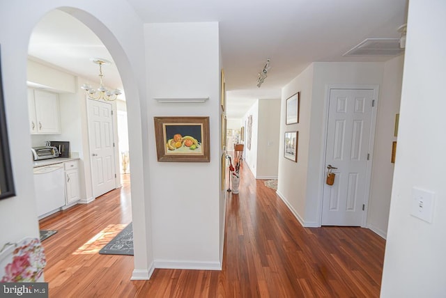 corridor featuring rail lighting, dark hardwood / wood-style floors, and a notable chandelier