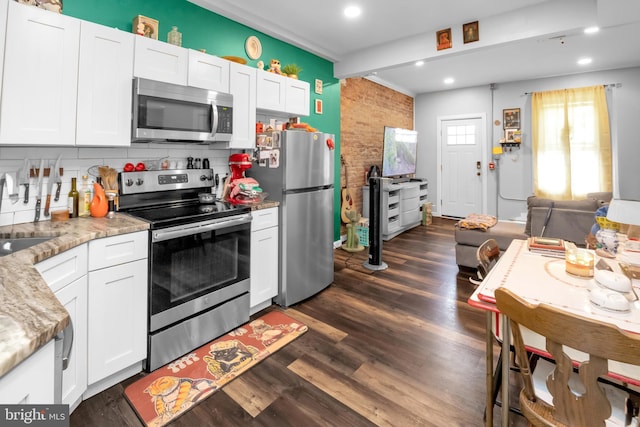 kitchen featuring dark wood-type flooring, light stone counters, backsplash, white cabinets, and appliances with stainless steel finishes