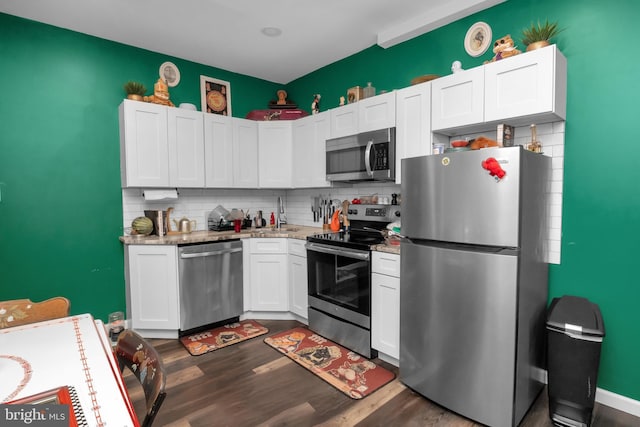 kitchen with dark wood-type flooring, decorative backsplash, light stone counters, white cabinetry, and stainless steel appliances