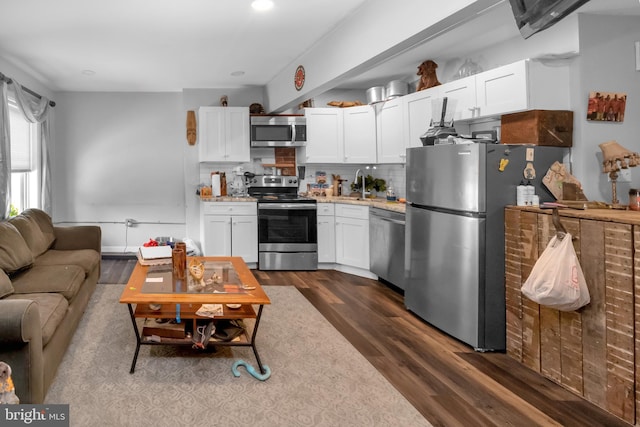 kitchen with tasteful backsplash, dark hardwood / wood-style flooring, white cabinets, and appliances with stainless steel finishes