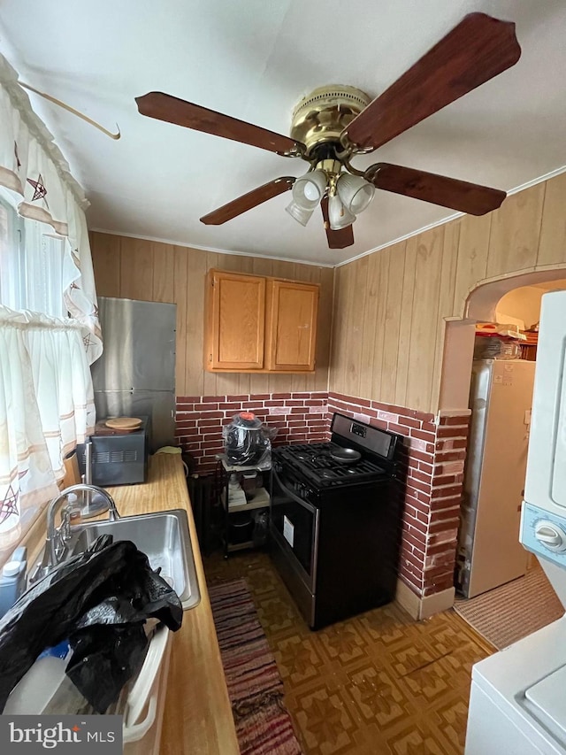 kitchen featuring gas range, ceiling fan, and wooden walls