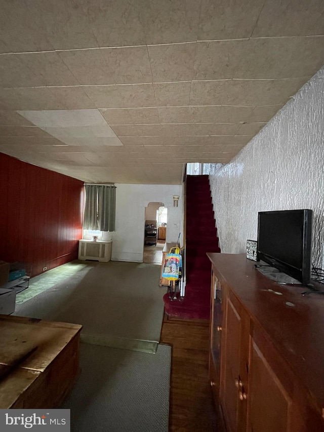 unfurnished living room with wood walls and dark colored carpet