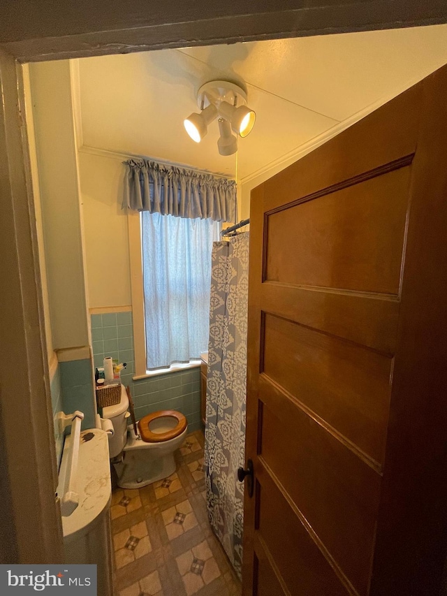 bathroom with tile walls and toilet