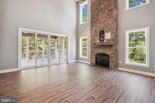 unfurnished living room featuring a fireplace, a towering ceiling, and hardwood / wood-style flooring