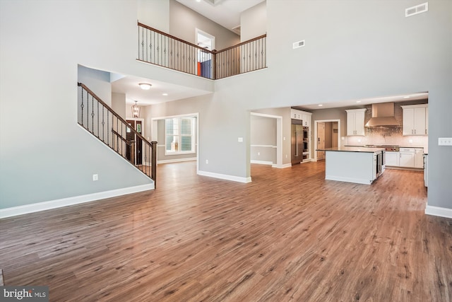 unfurnished living room with light hardwood / wood-style flooring and a high ceiling