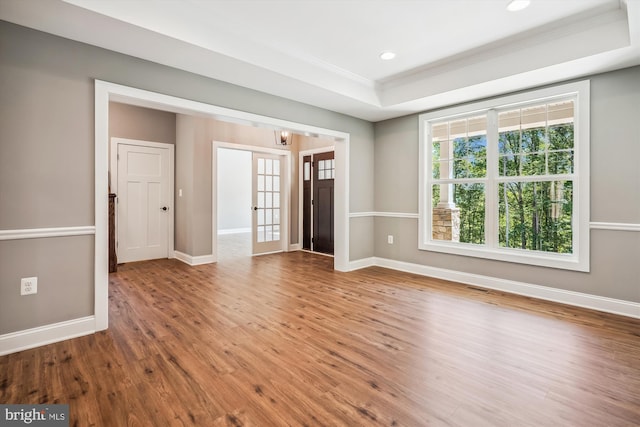 spare room featuring a tray ceiling, hardwood / wood-style flooring, and crown molding