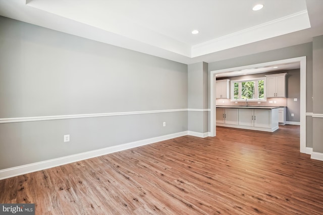 unfurnished living room featuring a raised ceiling and light wood-type flooring