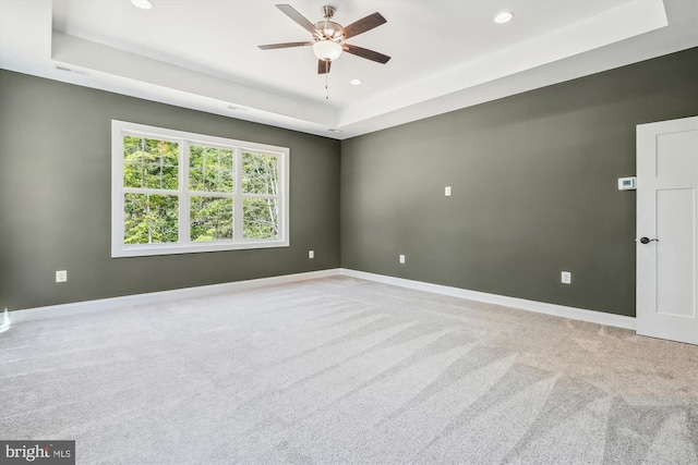 spare room featuring carpet, a raised ceiling, and ceiling fan