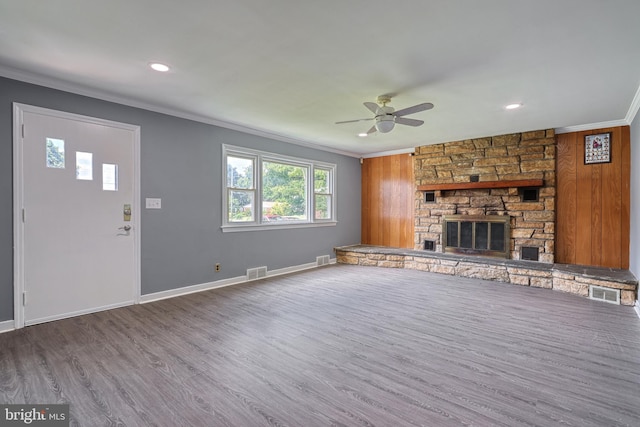 unfurnished living room featuring hardwood / wood-style floors, ceiling fan, ornamental molding, and a fireplace