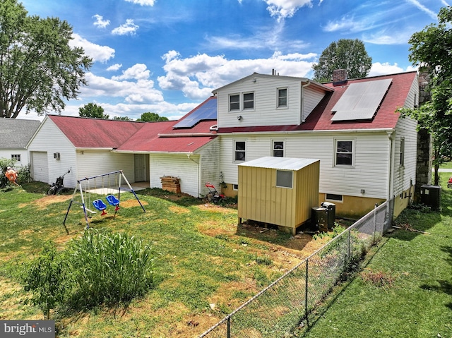 back of property featuring a storage shed, central AC, a lawn, and solar panels