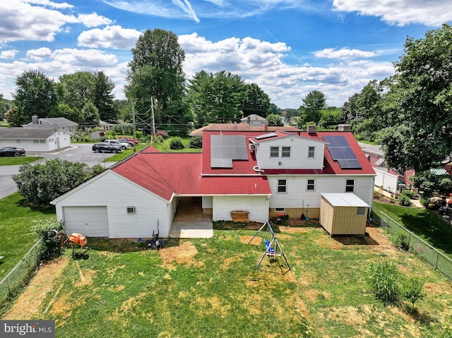 rear view of house featuring solar panels, a storage shed, and a lawn