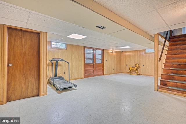 workout room with a paneled ceiling and wooden walls