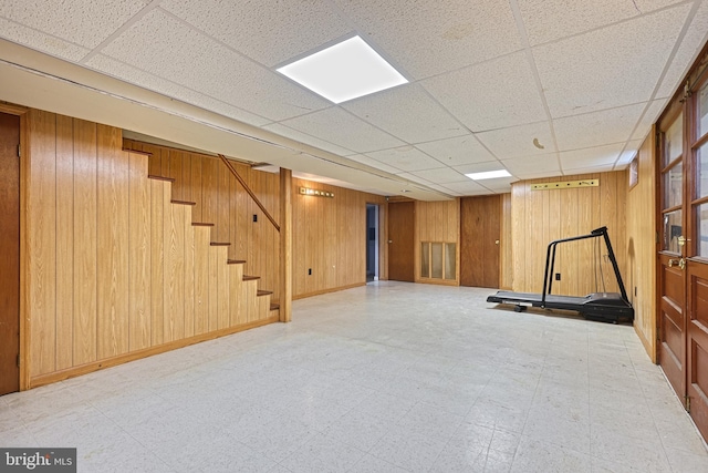 basement with a paneled ceiling and wooden walls