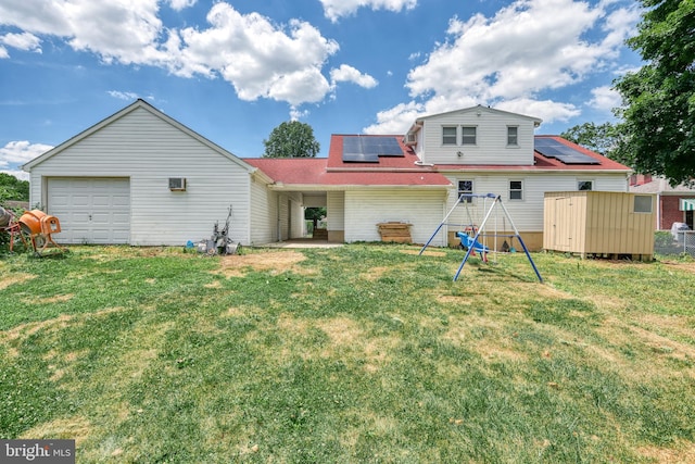 back of house with solar panels, a garage, a yard, a playground, and a shed