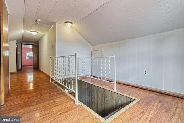 corridor with hardwood / wood-style floors and lofted ceiling