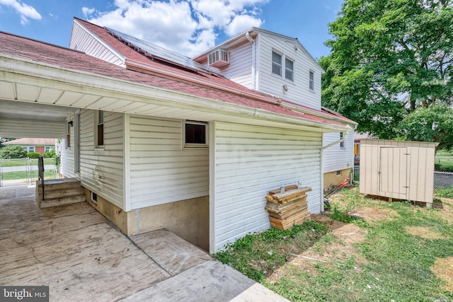 view of side of property with a storage shed and solar panels