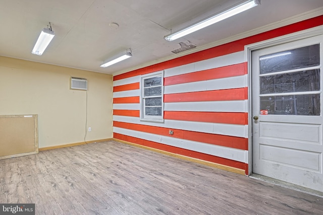 unfurnished room featuring a wall mounted air conditioner, wood-type flooring, and ornamental molding