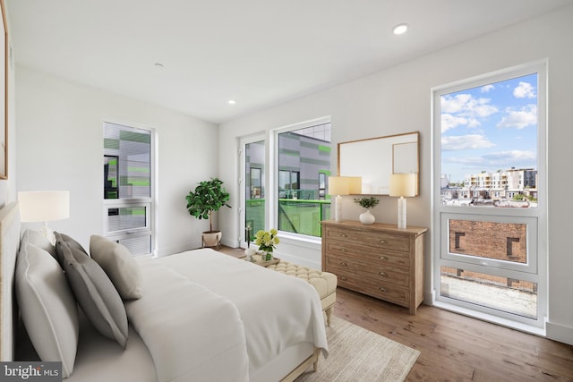 bedroom with hardwood / wood-style flooring, cooling unit, and multiple windows