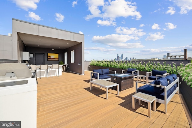 wooden deck featuring area for grilling, a bar, and an outdoor living space with a fire pit