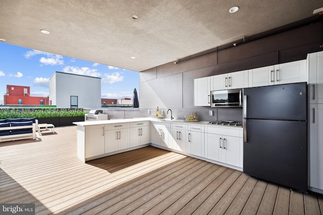 kitchen with kitchen peninsula, appliances with stainless steel finishes, light wood-type flooring, sink, and white cabinetry