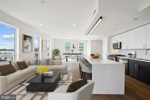 kitchen with tasteful backsplash, stainless steel appliances, sink, white cabinets, and a kitchen island