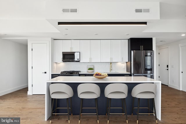 kitchen featuring a breakfast bar, a center island, sink, appliances with stainless steel finishes, and white cabinetry