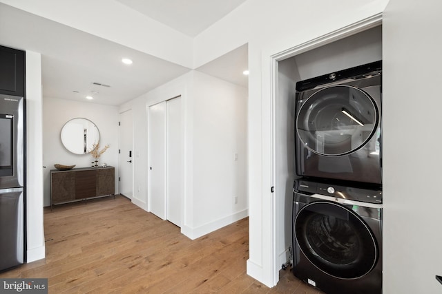 clothes washing area featuring stacked washer and dryer and light hardwood / wood-style floors