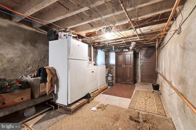 basement featuring washer and clothes dryer and white refrigerator