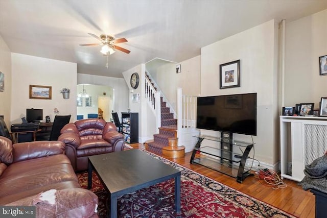 living room with ceiling fan with notable chandelier and hardwood / wood-style flooring