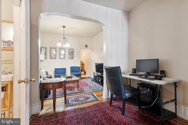 office with hardwood / wood-style floors and an inviting chandelier