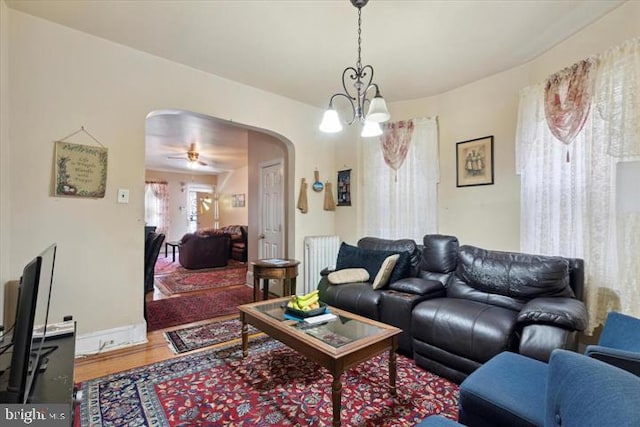 living room featuring hardwood / wood-style floors, ceiling fan with notable chandelier, and radiator heating unit