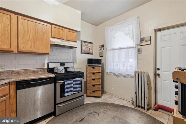 kitchen featuring decorative backsplash, radiator heating unit, stainless steel appliances, and light tile patterned floors