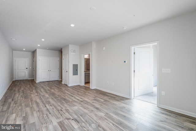 interior space with light wood finished floors, electric panel, and baseboards