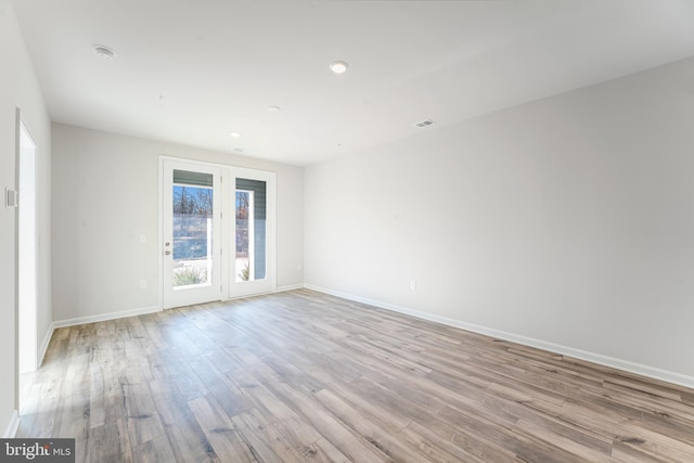 empty room featuring visible vents, light wood-style flooring, and baseboards