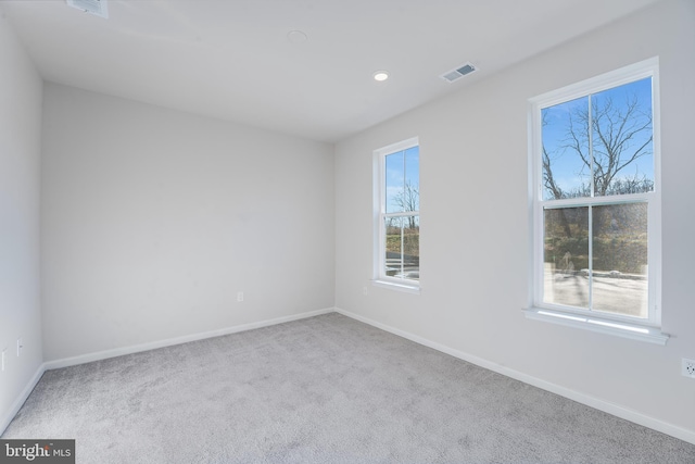 empty room with carpet floors, visible vents, and baseboards