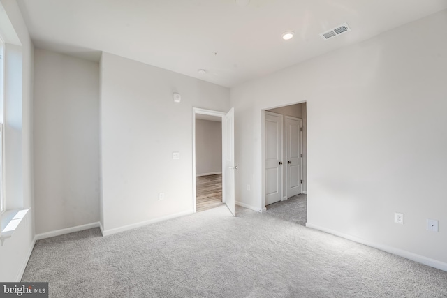 unfurnished room featuring carpet, visible vents, baseboards, and recessed lighting