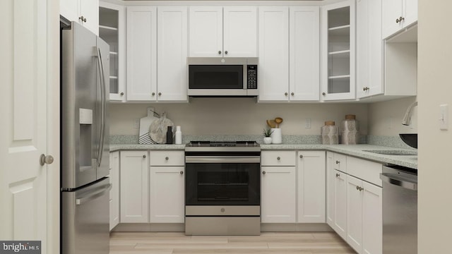 kitchen featuring white cabinets, light stone countertops, sink, and appliances with stainless steel finishes