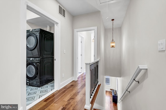 laundry room with wood-type flooring and stacked washer and clothes dryer