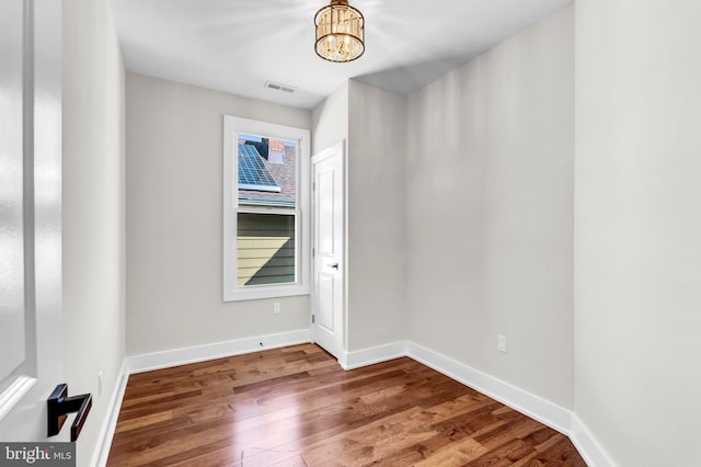 empty room with a notable chandelier and wood-type flooring