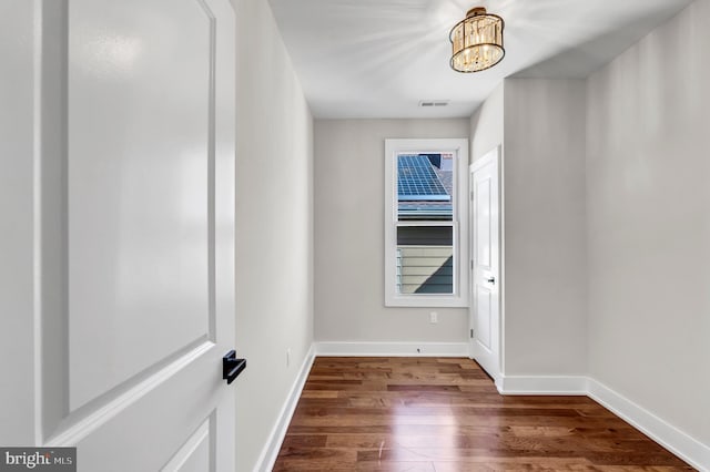 empty room featuring wood-type flooring and an inviting chandelier