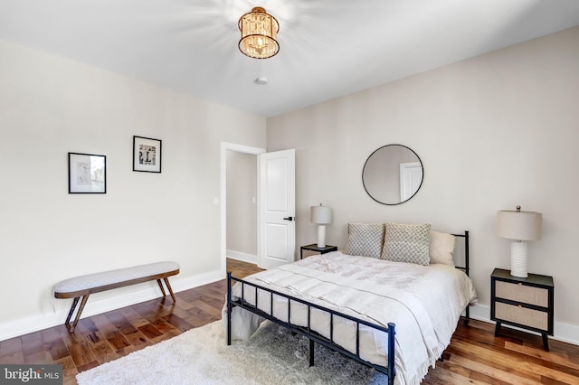 bedroom featuring wood-type flooring and an inviting chandelier