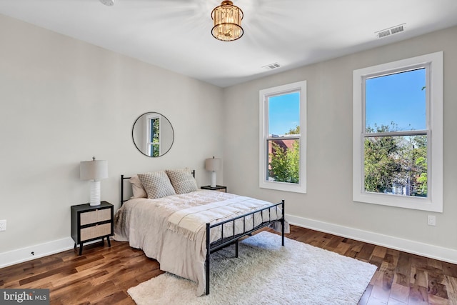 bedroom featuring a chandelier and dark wood-type flooring