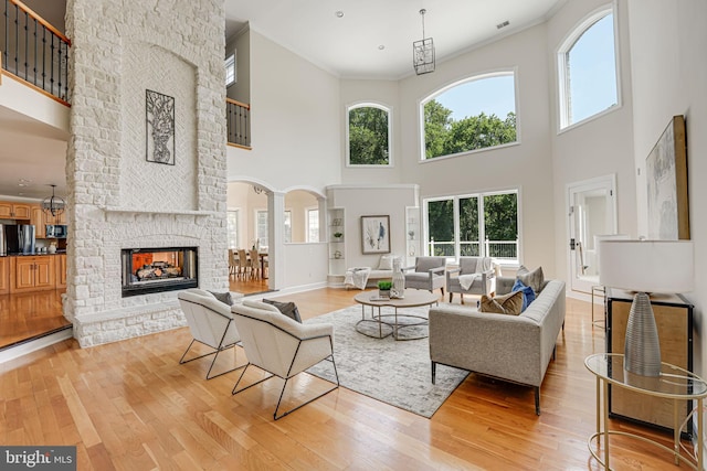 living room featuring a multi sided fireplace, a high ceiling, ornamental molding, and light hardwood / wood-style floors