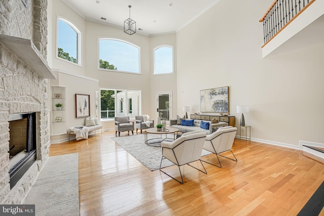 living room featuring light hardwood / wood-style flooring, built in features, crown molding, and a fireplace