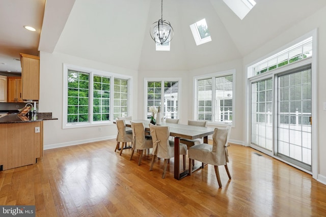 interior space featuring light wood-type flooring, a skylight, a notable chandelier, and a healthy amount of sunlight