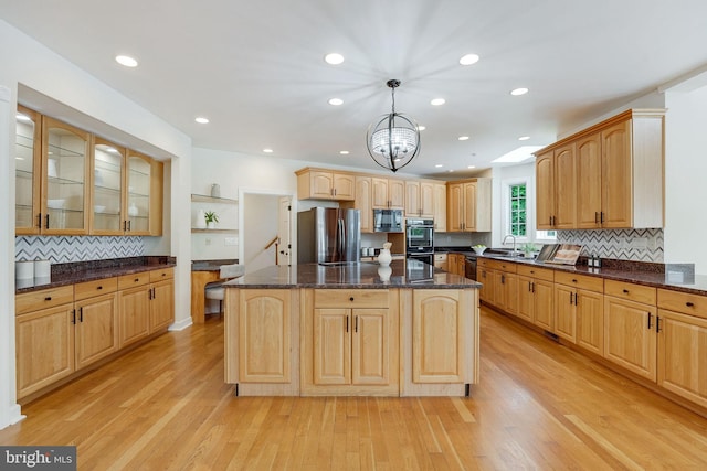 kitchen with dark stone countertops, a center island, hanging light fixtures, and black appliances